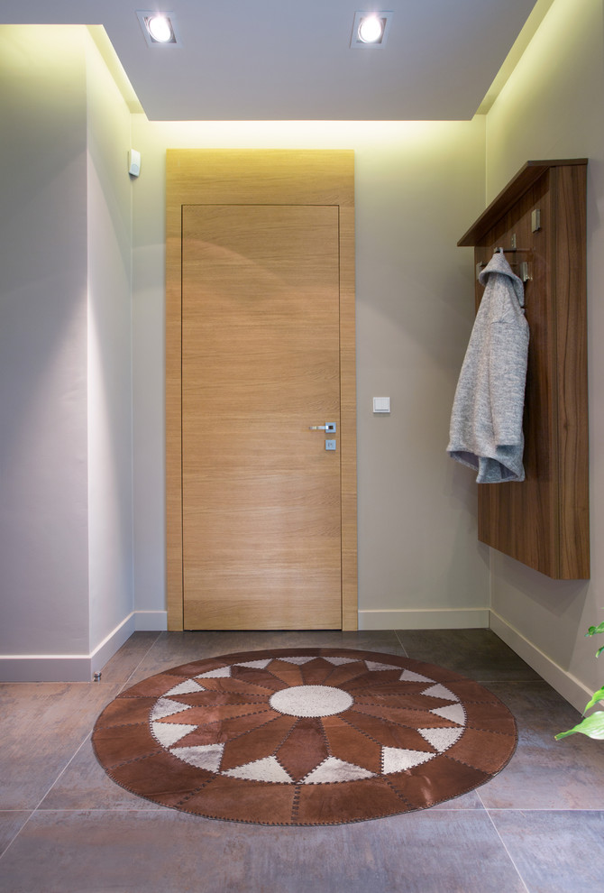 Diseño de puerta principal de estilo americano de tamaño medio con paredes grises, suelo de baldosas de porcelana, puerta simple, puerta de madera clara y suelo marrón