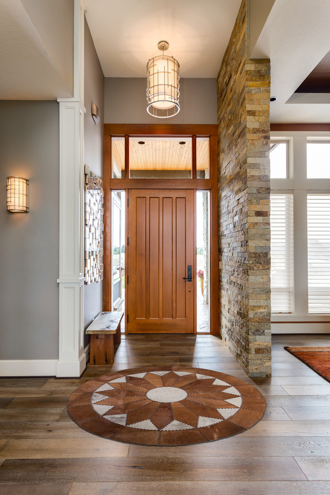 Inspiration for a mid-sized southwestern medium tone wood floor and brown floor entryway remodel in Los Angeles with gray walls and a medium wood front door