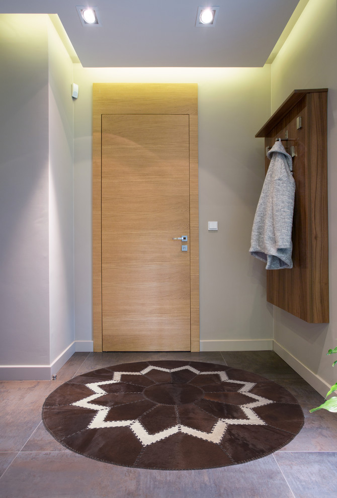 Esempio di una porta d'ingresso minimalista di medie dimensioni con pareti grigie, pavimento in gres porcellanato, una porta singola, una porta in legno chiaro e pavimento grigio
