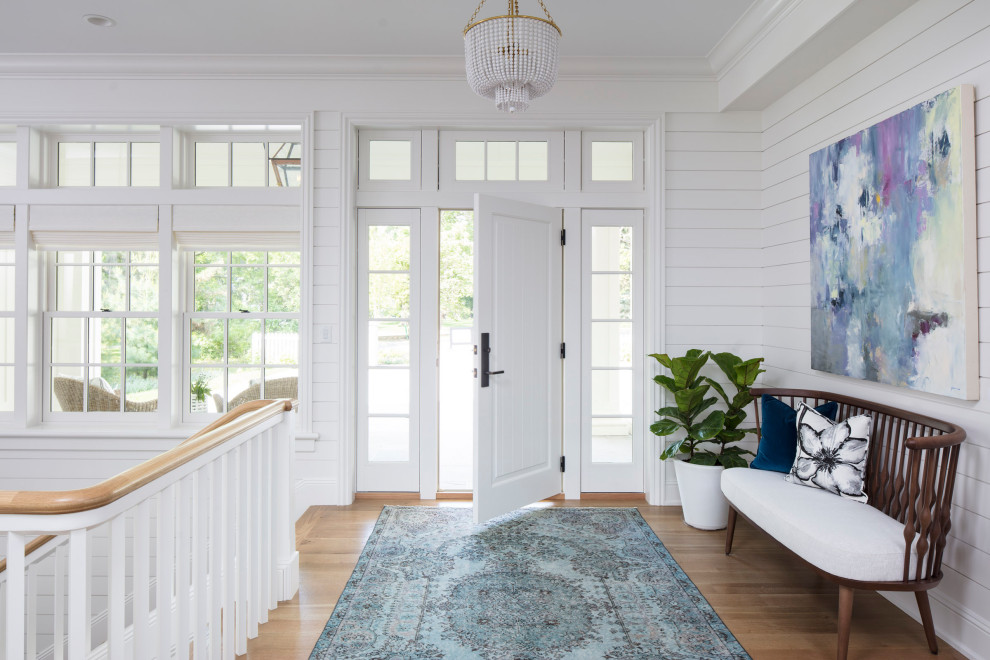 Inspiration pour un hall d'entrée traditionnel de taille moyenne avec un mur blanc, un sol en bois brun, une porte simple, une porte blanche et un sol marron.