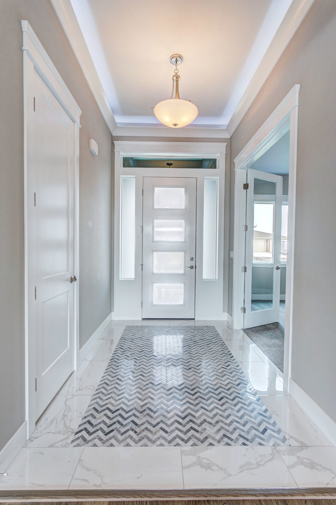 Идея дизайна: узкая прихожая среднего размера в стиле неоклассика (современная классика) с серыми стенами, мраморным полом, одностворчатой входной дверью, белой входной дверью и белым полом