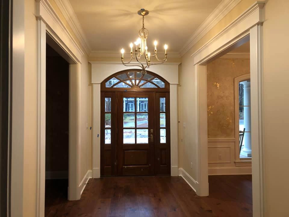 Réalisation d'un grand hall d'entrée avec un mur beige, parquet foncé, une porte simple, une porte en verre et un sol marron.