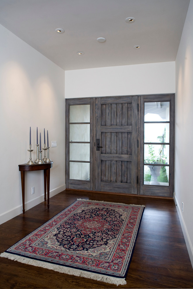 Foto de entrada mediterránea con paredes blancas, suelo de madera oscura, puerta simple y puerta de madera en tonos medios