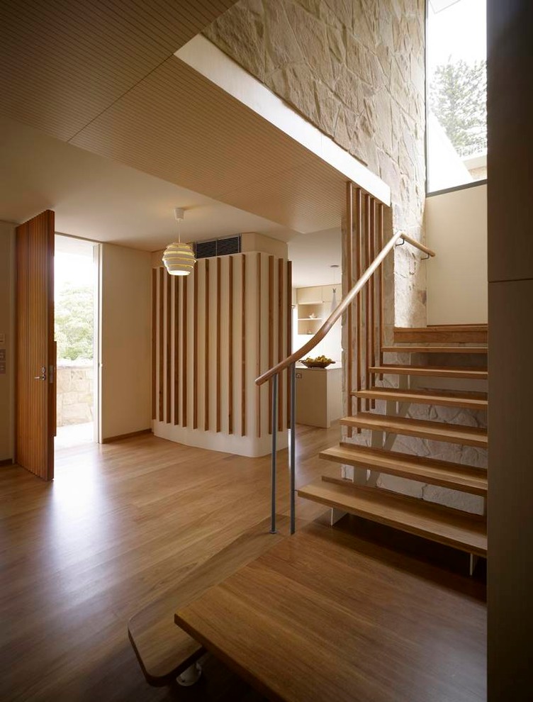 Diseño de distribuidor moderno con paredes beige, suelo de madera en tonos medios, puerta simple, puerta de madera en tonos medios y suelo marrón