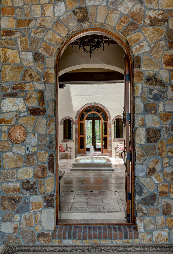 На фото: входная дверь в средиземноморском стиле с черными стенами, одностворчатой входной дверью и коричневой входной дверью с