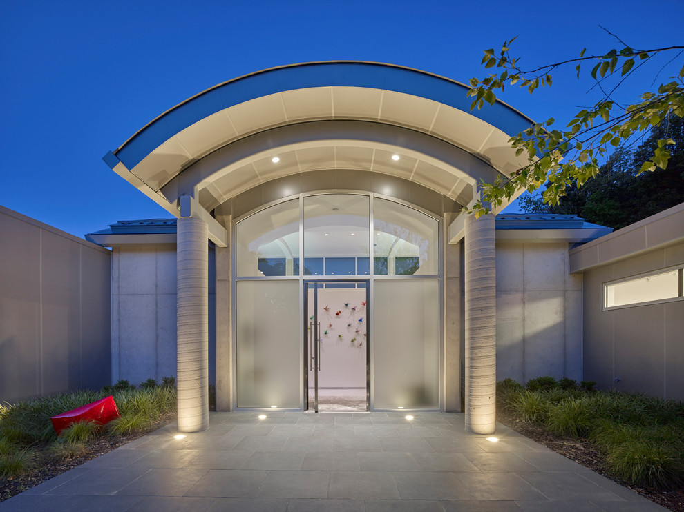 Réalisation d'une porte d'entrée minimaliste de taille moyenne avec une porte pivot, un sol gris et une porte en verre.