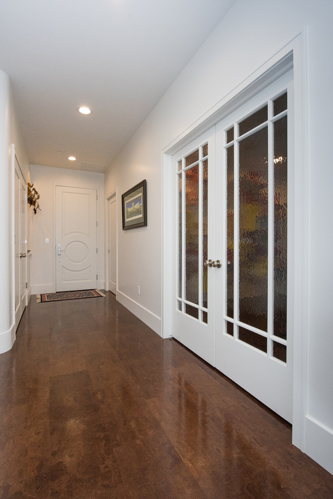 На фото: фойе в современном стиле с белыми стенами, пробковым полом, одностворчатой входной дверью, белой входной дверью и коричневым полом с