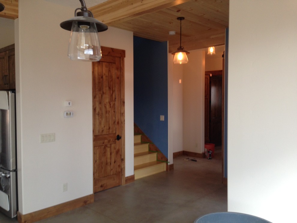 Photo of a country foyer in Salt Lake City with white walls, concrete flooring and a glass front door.