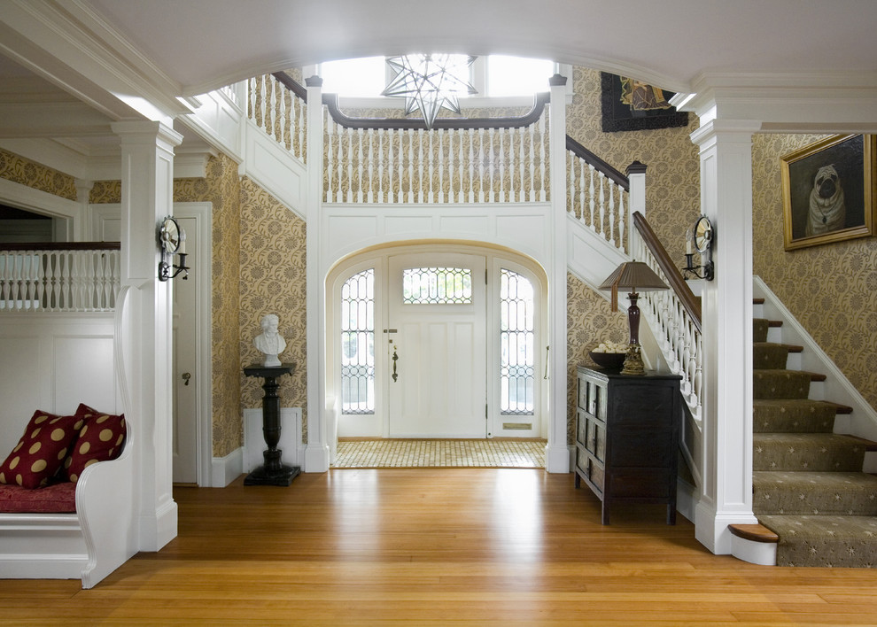 Inspiration for a large coastal medium tone wood floor entryway remodel in Boston with beige walls and a white front door