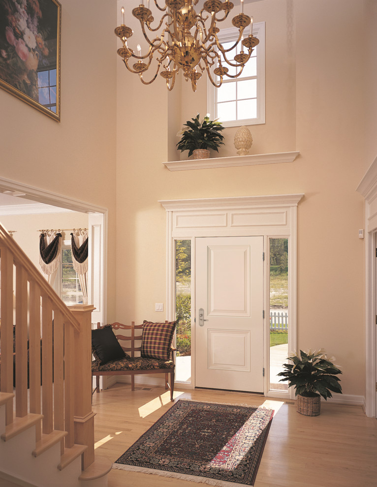Foto de distribuidor clásico con paredes beige, suelo de madera clara, puerta simple y puerta blanca