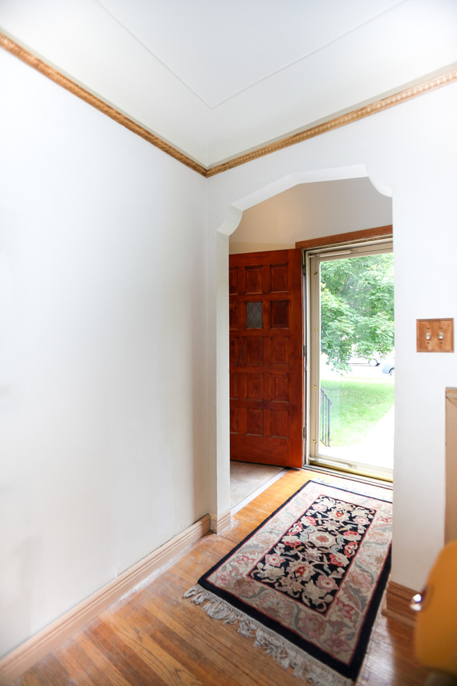 Imagen de puerta principal clásica renovada de tamaño medio con paredes blancas, suelo de madera en tonos medios, puerta simple, puerta de madera oscura y suelo marrón