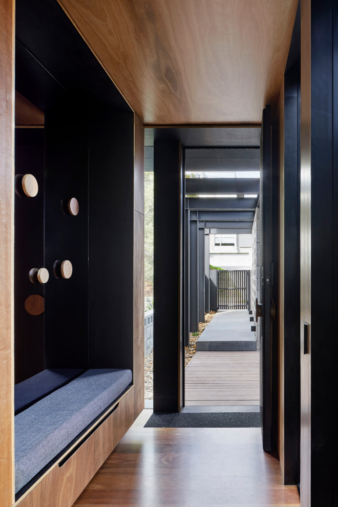 Cette image montre une porte d'entrée minimaliste de taille moyenne avec un mur marron, un sol en bois brun, une porte simple, une porte en bois brun, un sol marron, un plafond en lambris de bois et du lambris.