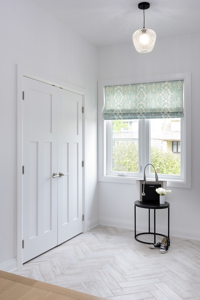 Imagen de entrada actual con paredes blancas, suelo de baldosas de porcelana, puerta simple y puerta blanca