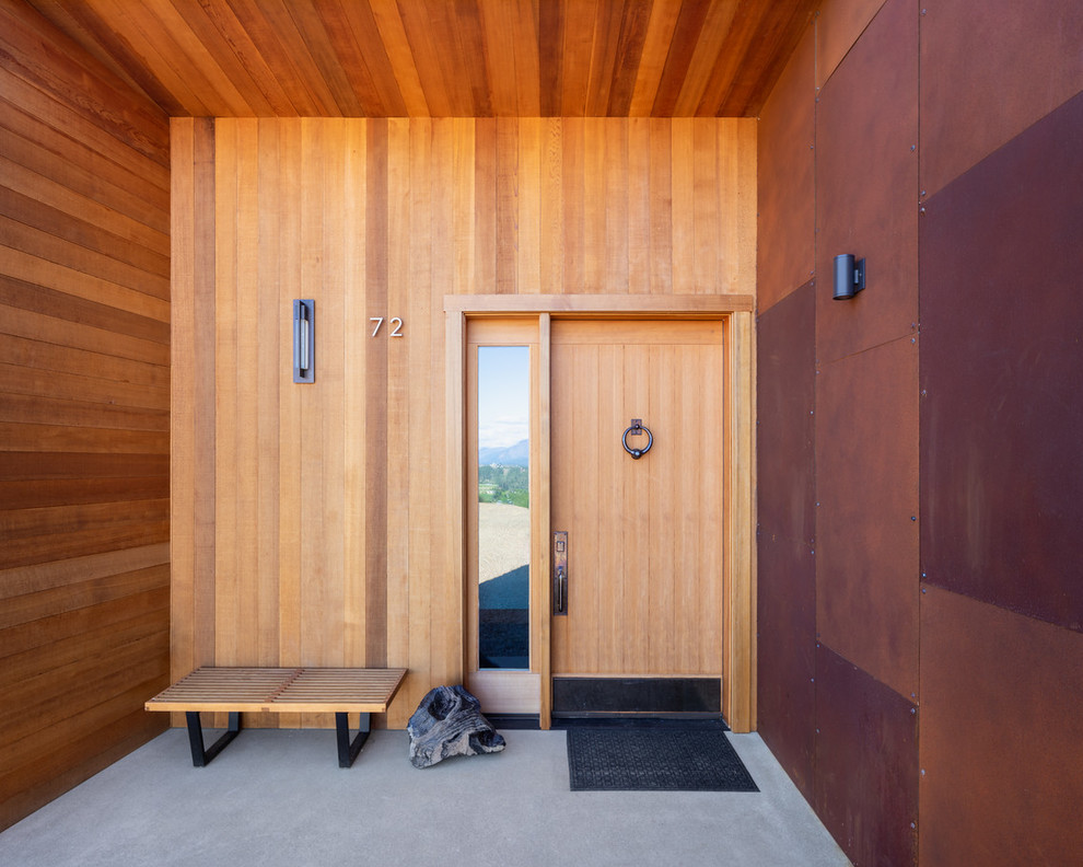 Ispirazione per una porta d'ingresso minimal di medie dimensioni con pareti marroni, pavimento in cemento, una porta singola, pavimento grigio e una porta in legno chiaro