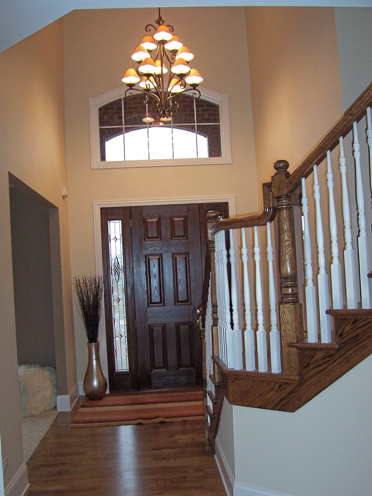Ispirazione per un grande ingresso tradizionale con pareti beige, pavimento in legno massello medio, una porta singola e una porta in legno scuro