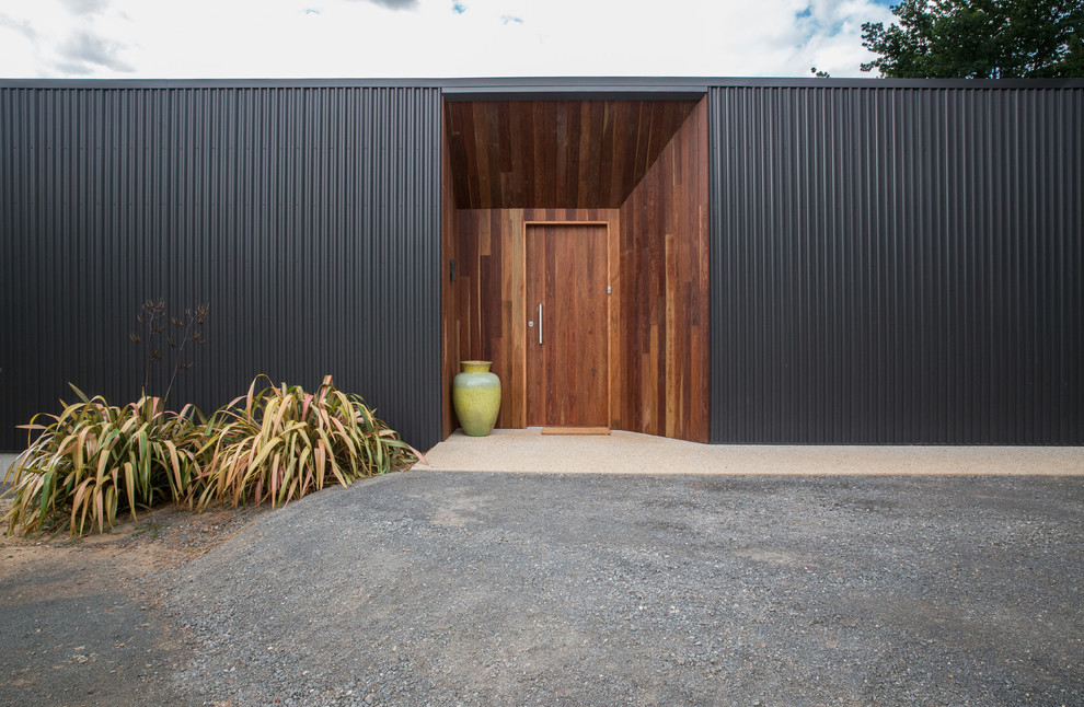 Imagen de puerta principal contemporánea de tamaño medio con paredes negras, suelo de granito, puerta simple, puerta de madera oscura y suelo beige