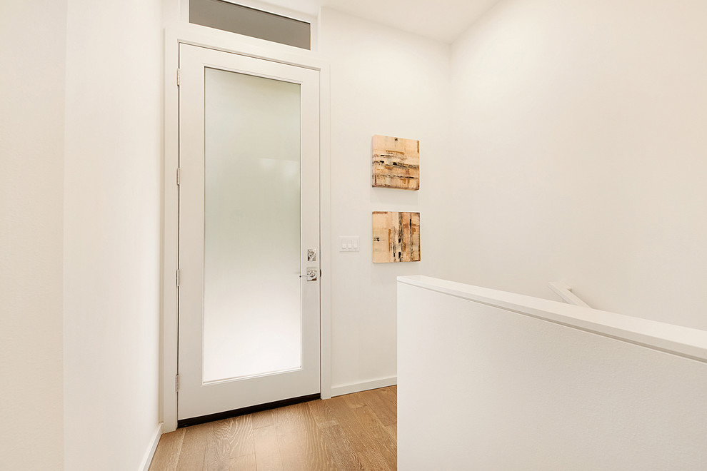 Стильный дизайн: узкая прихожая среднего размера в стиле неоклассика (современная классика) с белыми стенами, паркетным полом среднего тона, одностворчатой входной дверью, белой входной дверью и коричневым полом - последний тренд