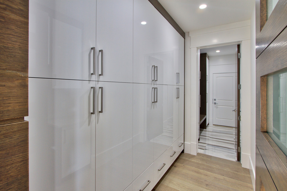 Idée de décoration pour une très grande entrée minimaliste avec un vestiaire, un mur blanc, un sol en marbre, une porte simple et une porte en bois brun.