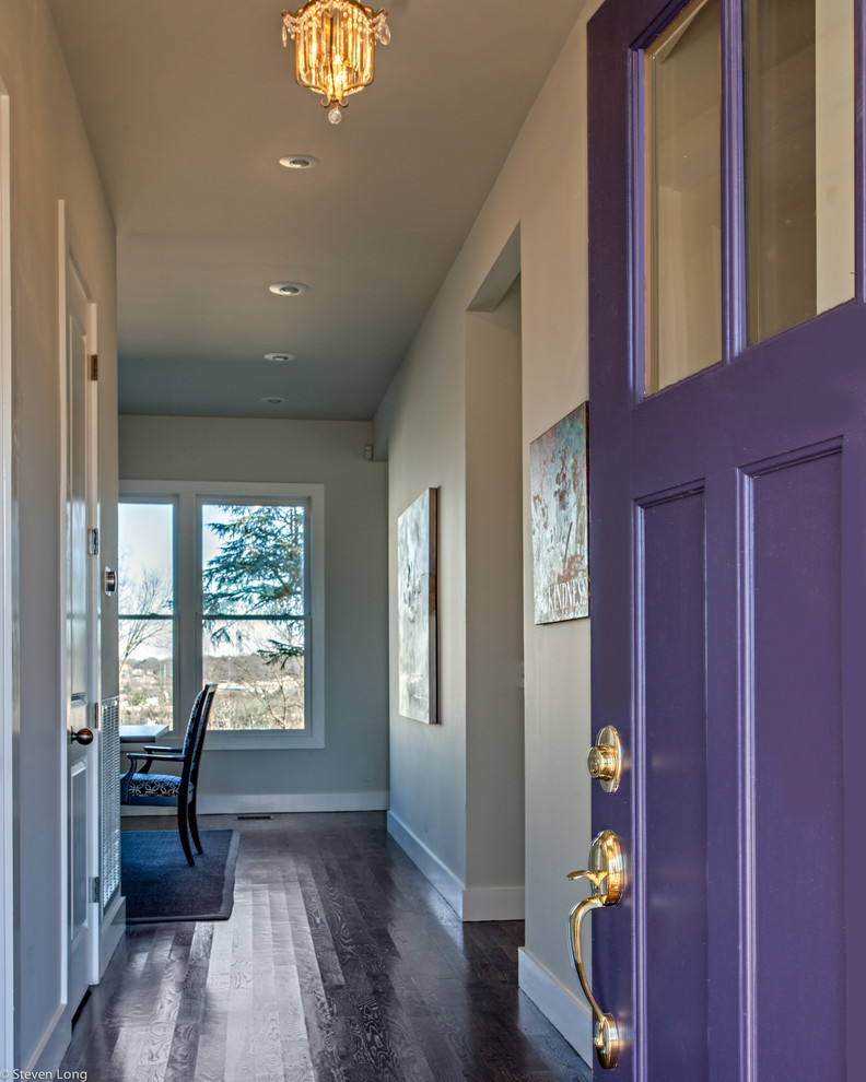 Lantlig inredning av en stor ingång och ytterdörr, med vita väggar, en enkeldörr och en lila dörr