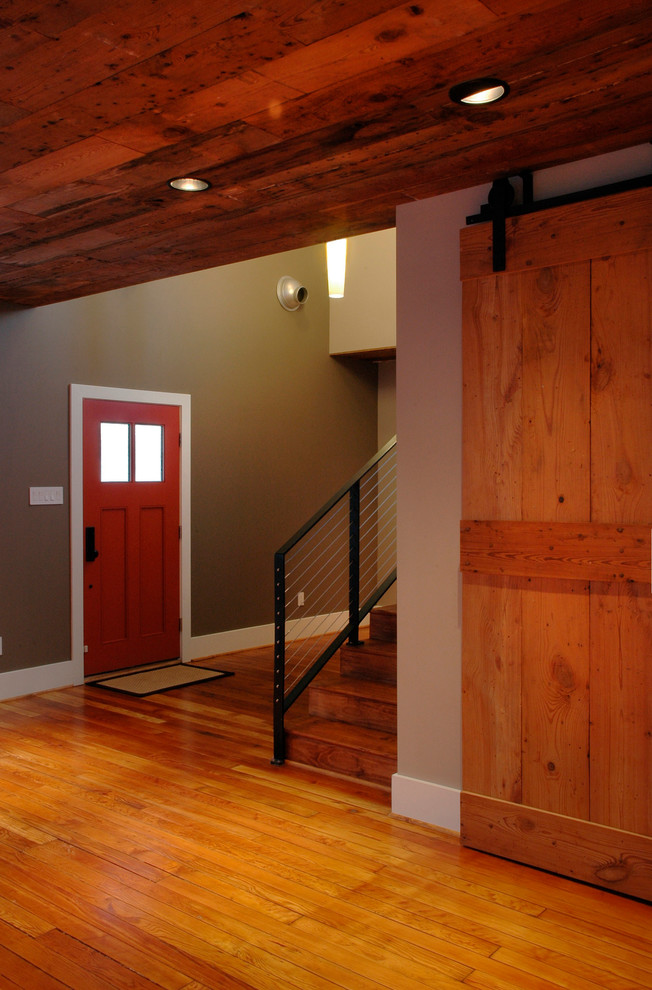Réalisation d'une porte d'entrée craftsman de taille moyenne avec un mur multicolore, un sol en bois brun, une porte simple et une porte rouge.