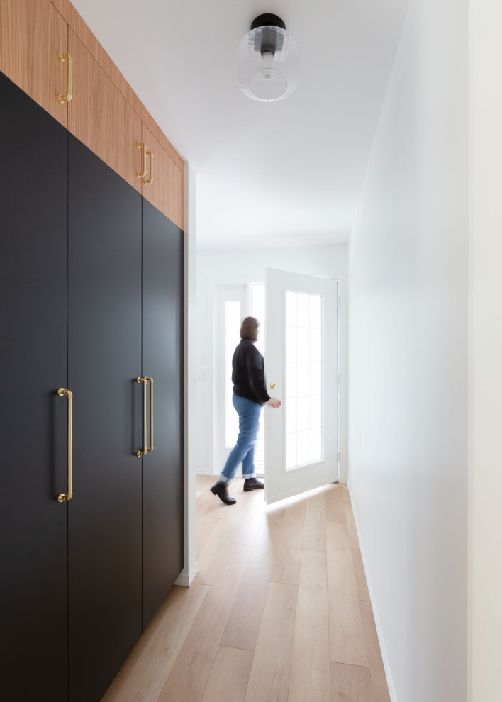 Aménagement d'une entrée scandinave de taille moyenne avec un couloir, un mur blanc, parquet clair, une porte simple, une porte en verre et un sol marron.