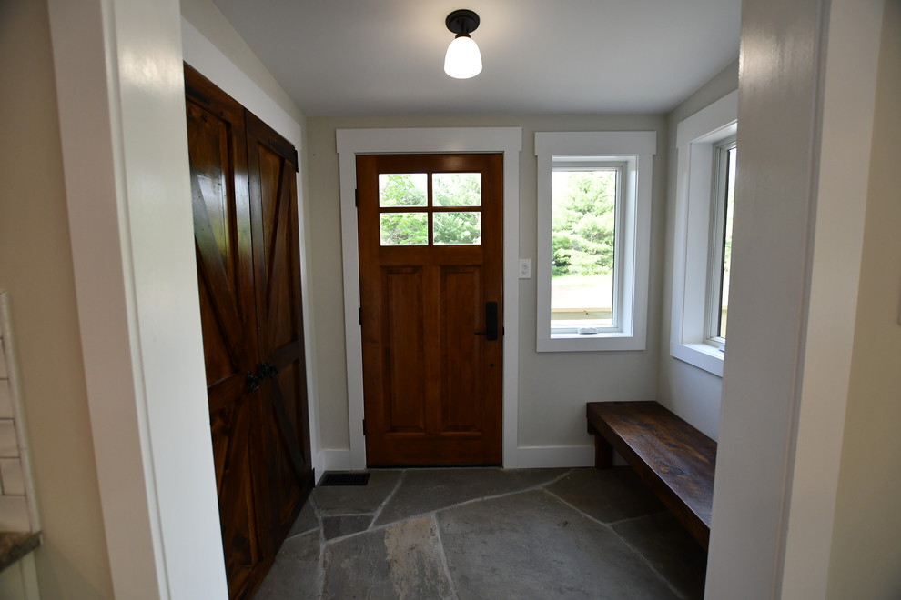 Ejemplo de distribuidor retro de tamaño medio con paredes grises, suelo de pizarra, puerta simple, puerta de madera en tonos medios y suelo gris