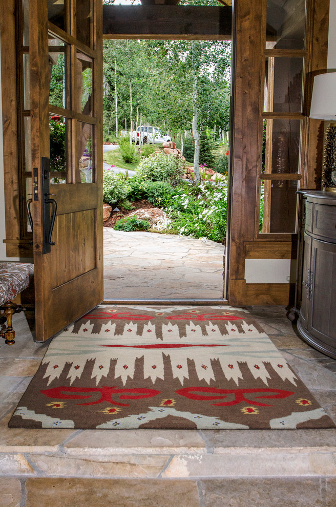 Imagen de puerta principal rural pequeña con paredes beige, suelo de pizarra, puerta simple y puerta de madera en tonos medios