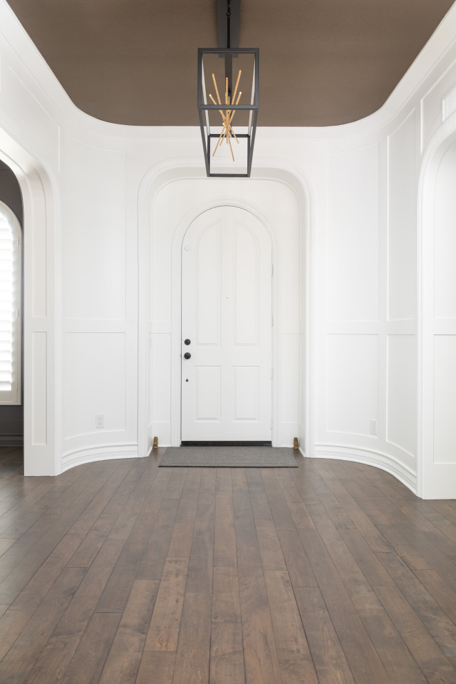 Immagine di un ingresso contemporaneo di medie dimensioni con pareti bianche, pavimento in legno massello medio, una porta singola, una porta bianca e pavimento marrone