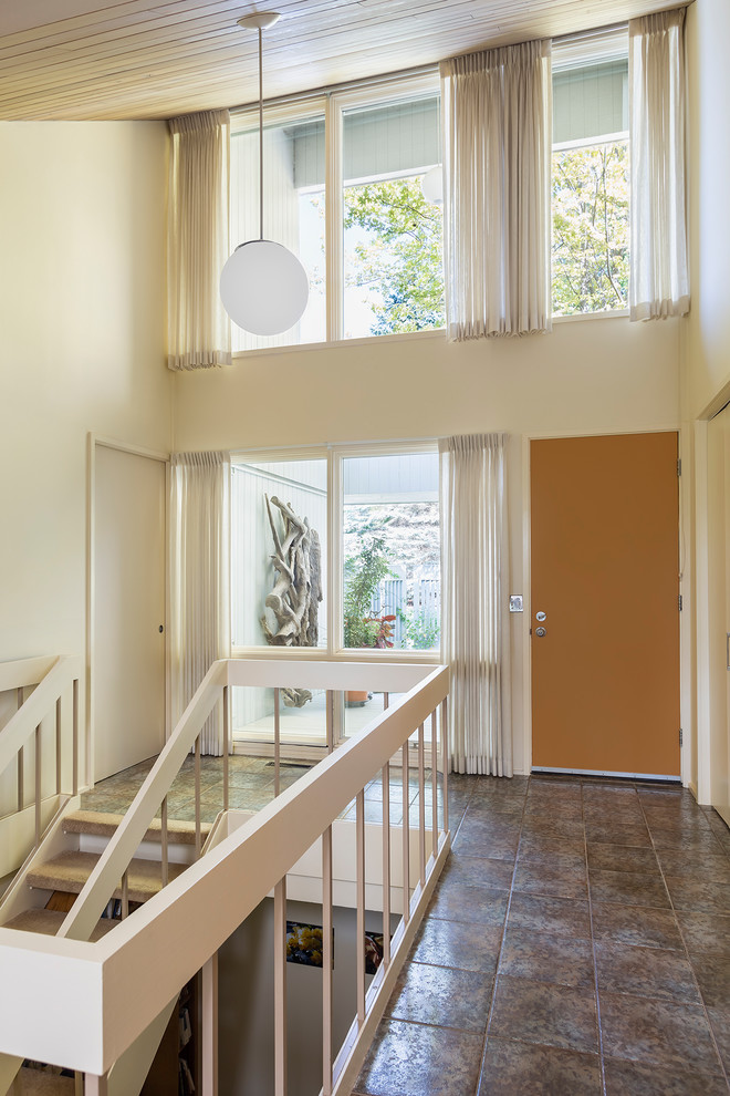 Ejemplo de entrada vintage con paredes blancas, suelo de baldosas de porcelana, puerta simple, puerta naranja y suelo gris