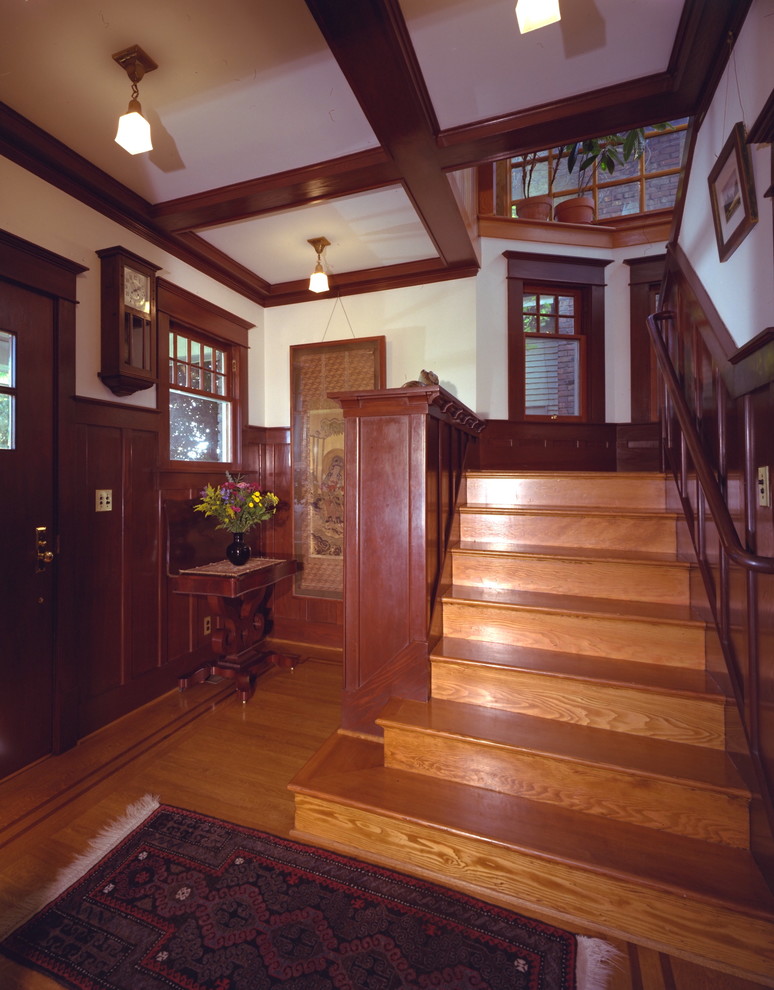 Idées déco pour un grand hall d'entrée craftsman avec un mur blanc, un sol en bois brun, une porte simple et une porte en bois foncé.