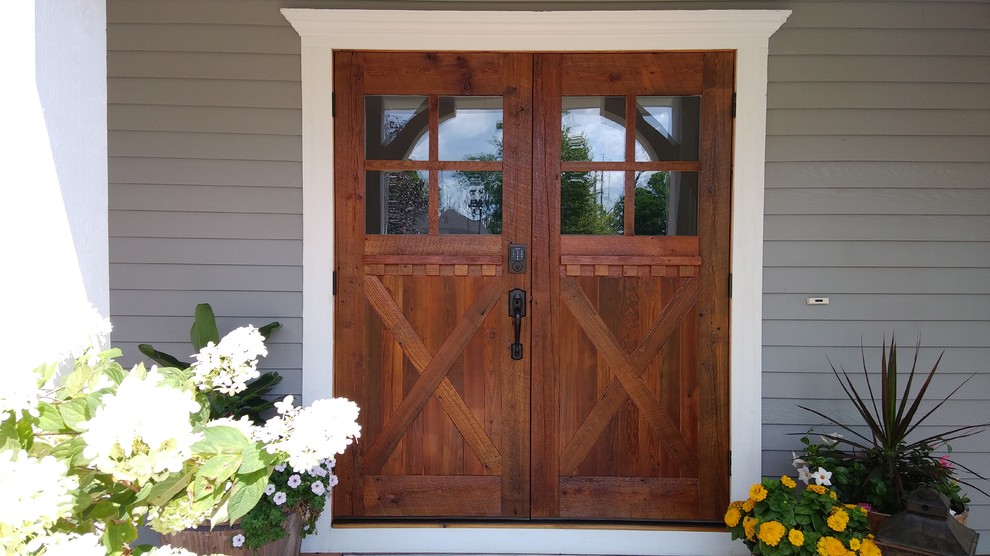 他の地域にある高級な広いカントリー風のおしゃれな玄関ドア (マルチカラーの壁、木目調のドア) の写真