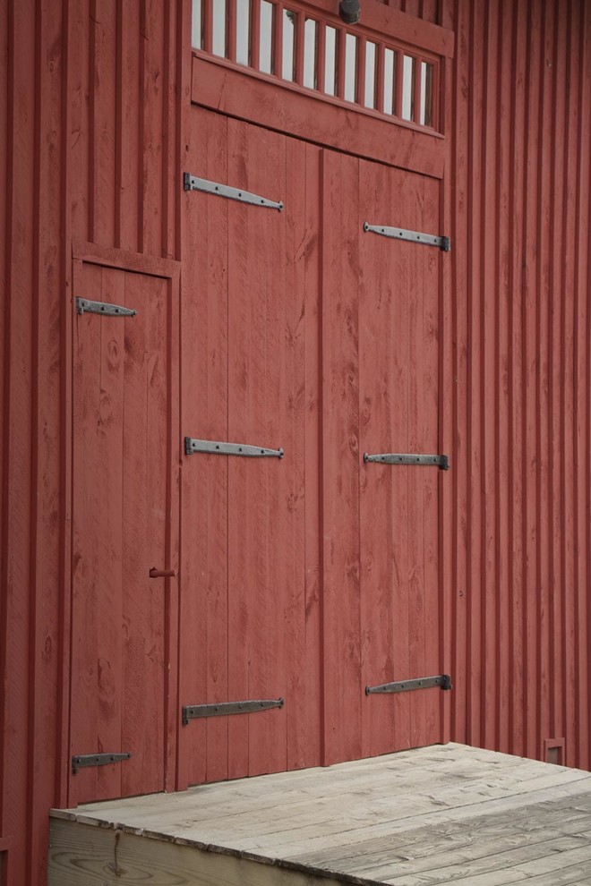 Exempel på en lantlig entré, med en dubbeldörr, röda väggar och en röd dörr