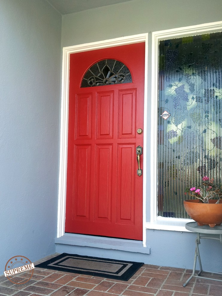 Стильный дизайн: входная дверь среднего размера в викторианском стиле с одностворчатой входной дверью, синими стенами, кирпичным полом и красной входной дверью - последний тренд