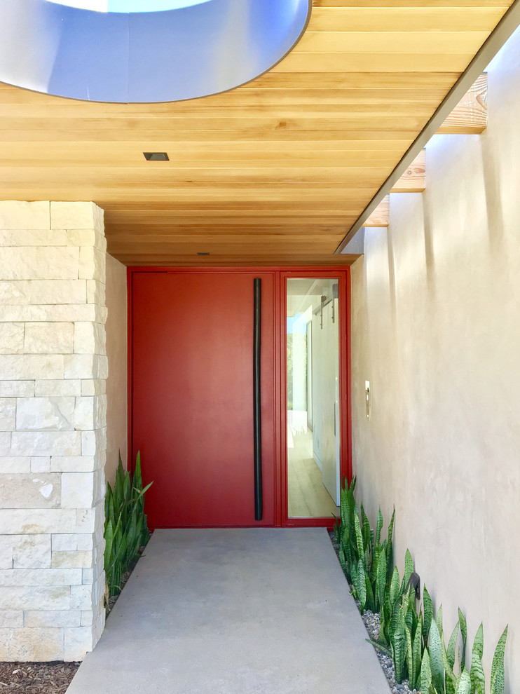 Foto på en stor funkis ingång och ytterdörr, med beige väggar, betonggolv, en pivotdörr, en röd dörr och grått golv