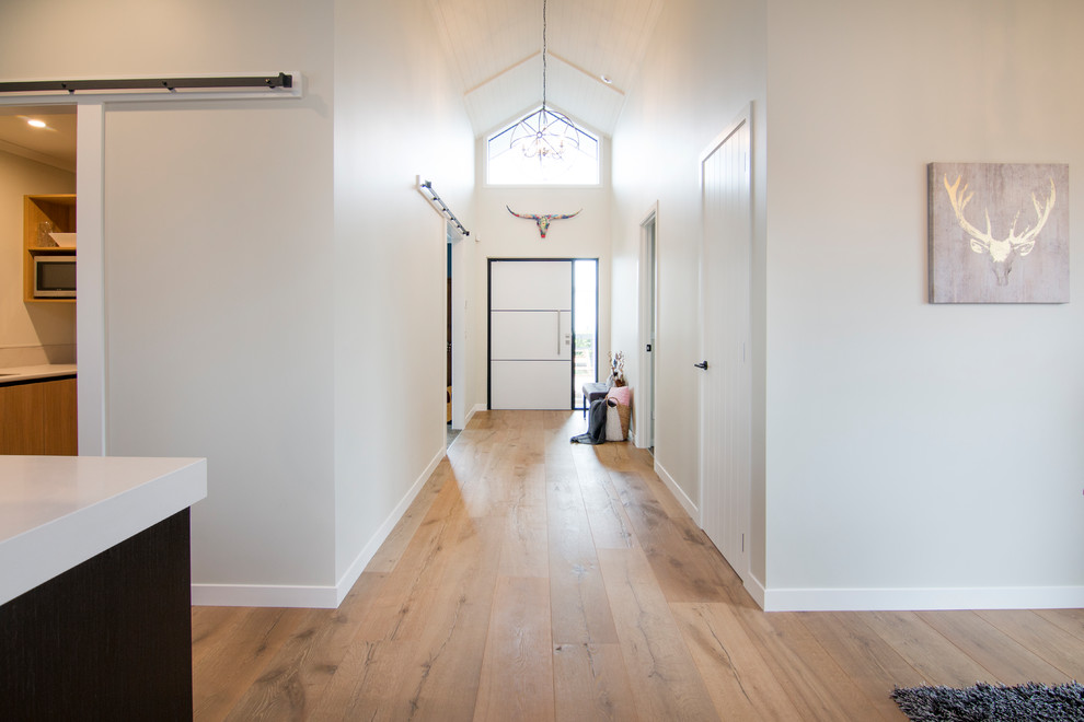 Inspiration for a mid-sized rustic medium tone wood floor and beige floor entryway remodel in Auckland with beige walls and a white front door