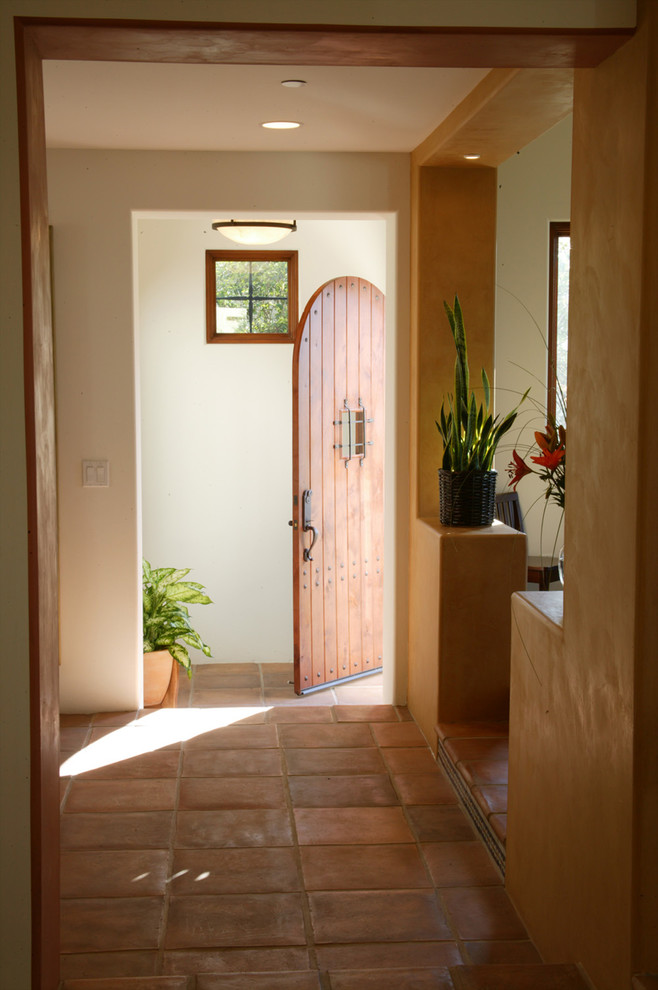 Exemple d'un hall d'entrée méditerranéen de taille moyenne avec un mur multicolore, tomettes au sol, une porte simple et une porte en bois brun.