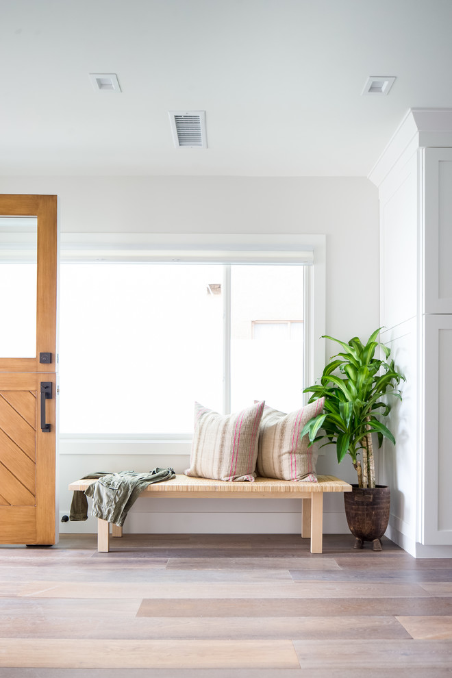 Maritime Haustür mit weißer Wandfarbe, braunem Holzboden, Klöntür, hellbrauner Holzhaustür und braunem Boden in Orange County