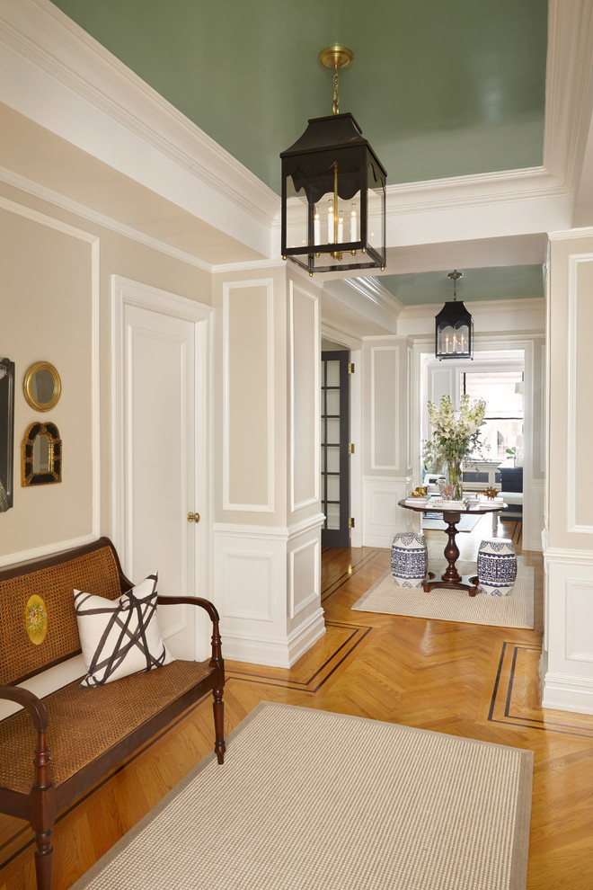 Mittelgroßes Klassisches Foyer mit beiger Wandfarbe, braunem Holzboden, Drehtür, schwarzer Haustür und braunem Boden in New York