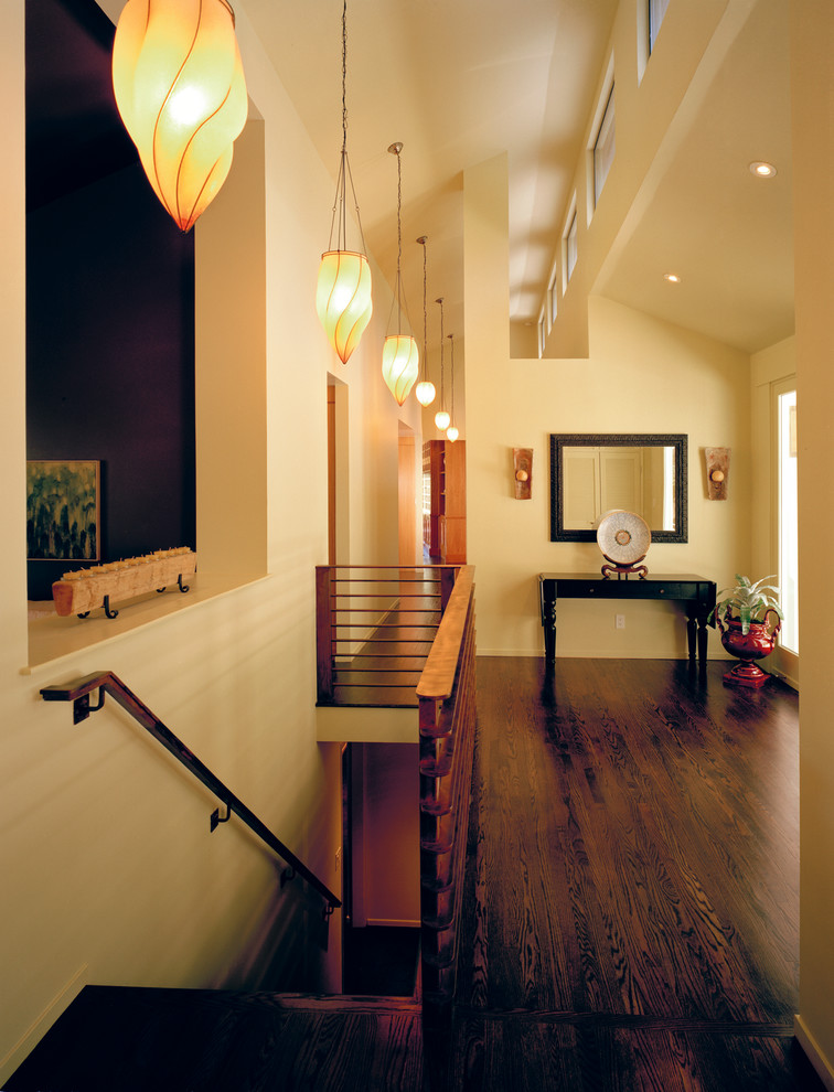 Idée de décoration pour une grande entrée design avec un couloir, un mur blanc, parquet foncé, une porte simple, une porte blanche et un sol marron.