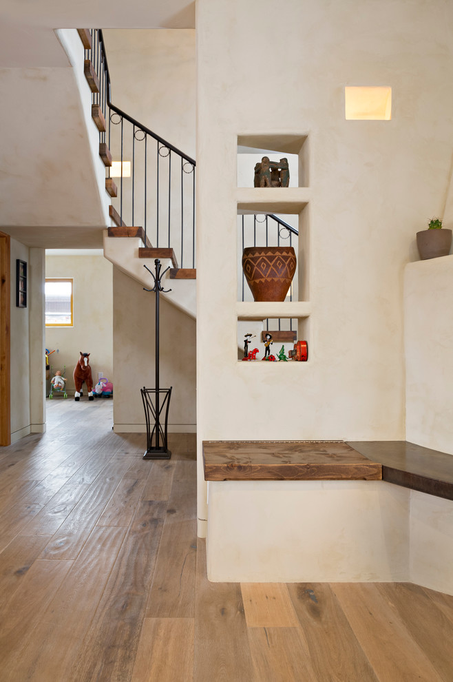 Réalisation d'une entrée méditerranéenne de taille moyenne avec un couloir, un mur blanc et parquet clair.