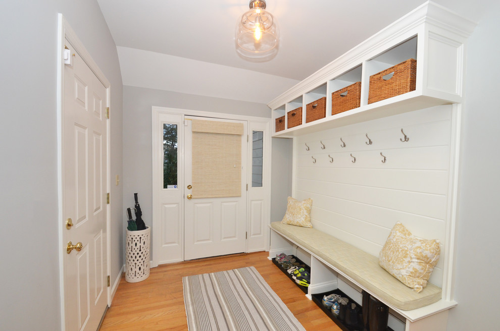 На фото: тамбур среднего размера в стиле неоклассика (современная классика) с серыми стенами, светлым паркетным полом, одностворчатой входной дверью и белой входной дверью