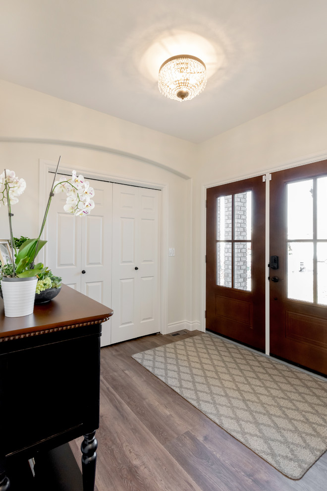 Réalisation d'une petite porte d'entrée tradition avec un mur blanc, un sol en vinyl, une porte double, une porte en bois brun et un sol marron.