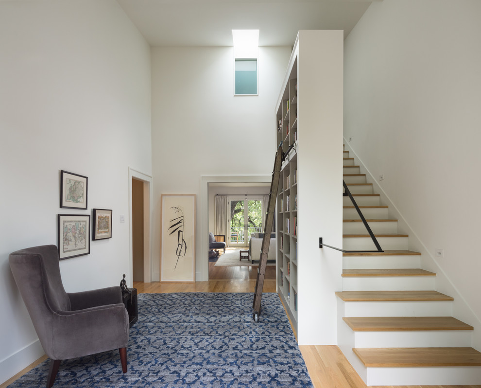 Idée de décoration pour un hall d'entrée design avec un mur blanc et un sol en bois brun.