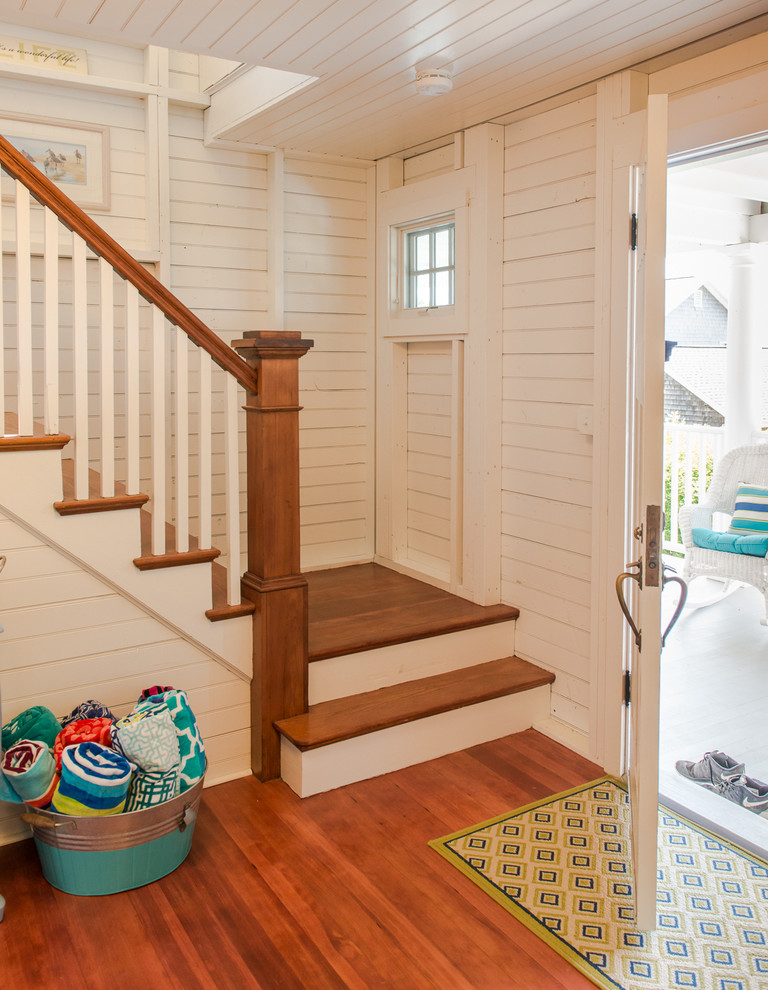 Example of a beach style medium tone wood floor entryway design in Boston with white walls