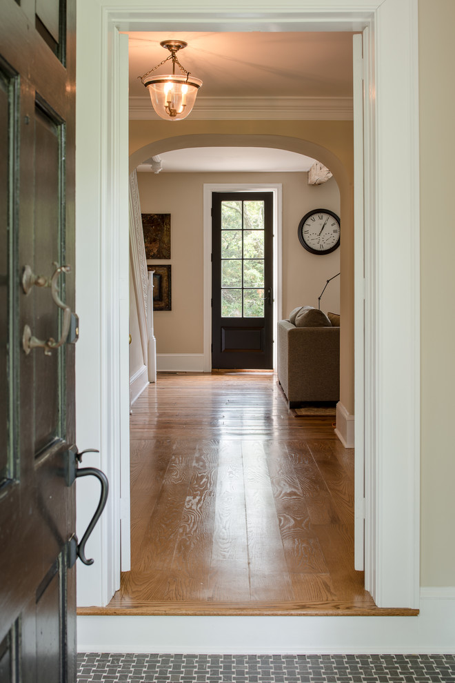 Idéer för att renovera en vintage entré, med beige väggar, mellanmörkt trägolv, en enkeldörr och en svart dörr