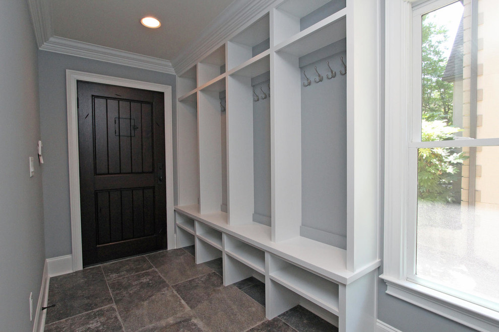 На фото: тамбур среднего размера в классическом стиле с серыми стенами, полом из сланца, одностворчатой входной дверью, входной дверью из темного дерева и коричневым полом с