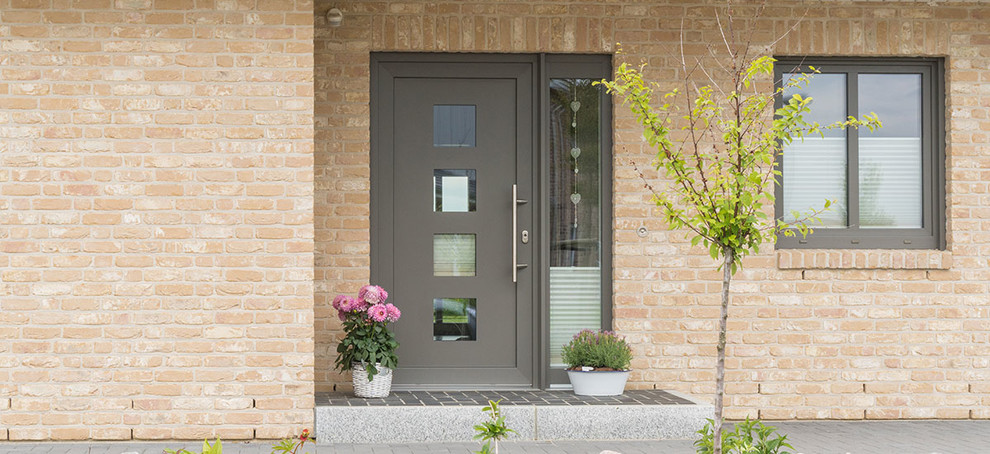 Inspiration pour une porte d'entrée design avec sol en béton ciré, une porte simple, une porte grise et un sol gris.