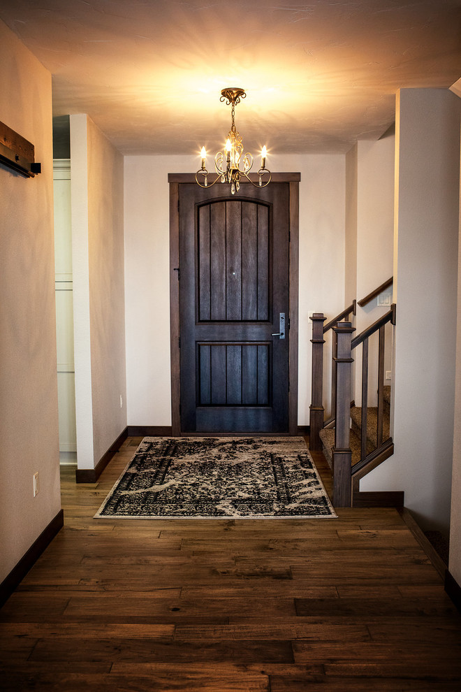 Réalisation d'une entrée tradition de taille moyenne avec un couloir, un mur blanc, parquet foncé, une porte simple, une porte en bois foncé et un sol marron.