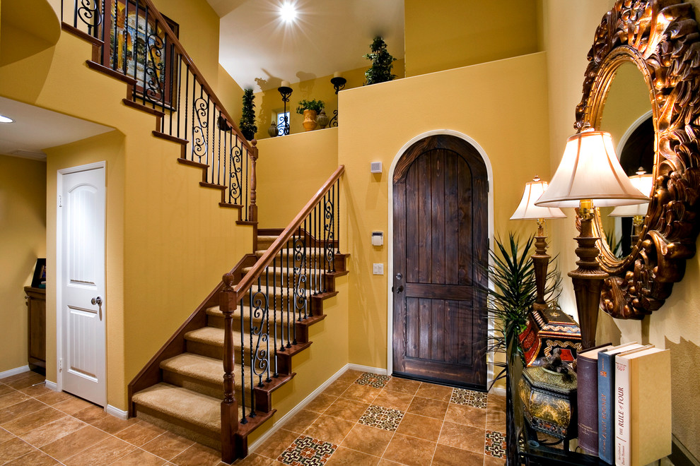 Mittelgroßes Mediterranes Foyer mit gelber Wandfarbe, Marmorboden, Einzeltür und dunkler Holzhaustür in Orange County