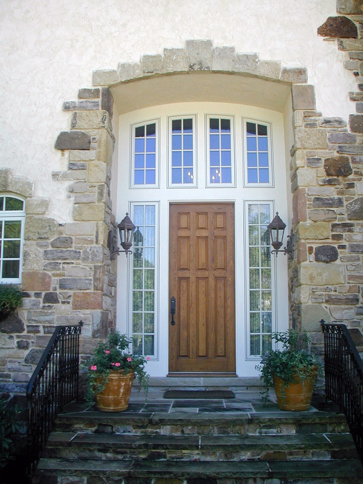 Immagine di una grande porta d'ingresso classica con una porta singola e una porta in legno bruno